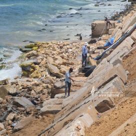 بالصور: عمال بناء فلسطينيون يبنون جدارًا بحريًا ، من أنقاض المباني المدمرة لمنع  تآكل الساحل بالقرب من مخيم الشاطئ